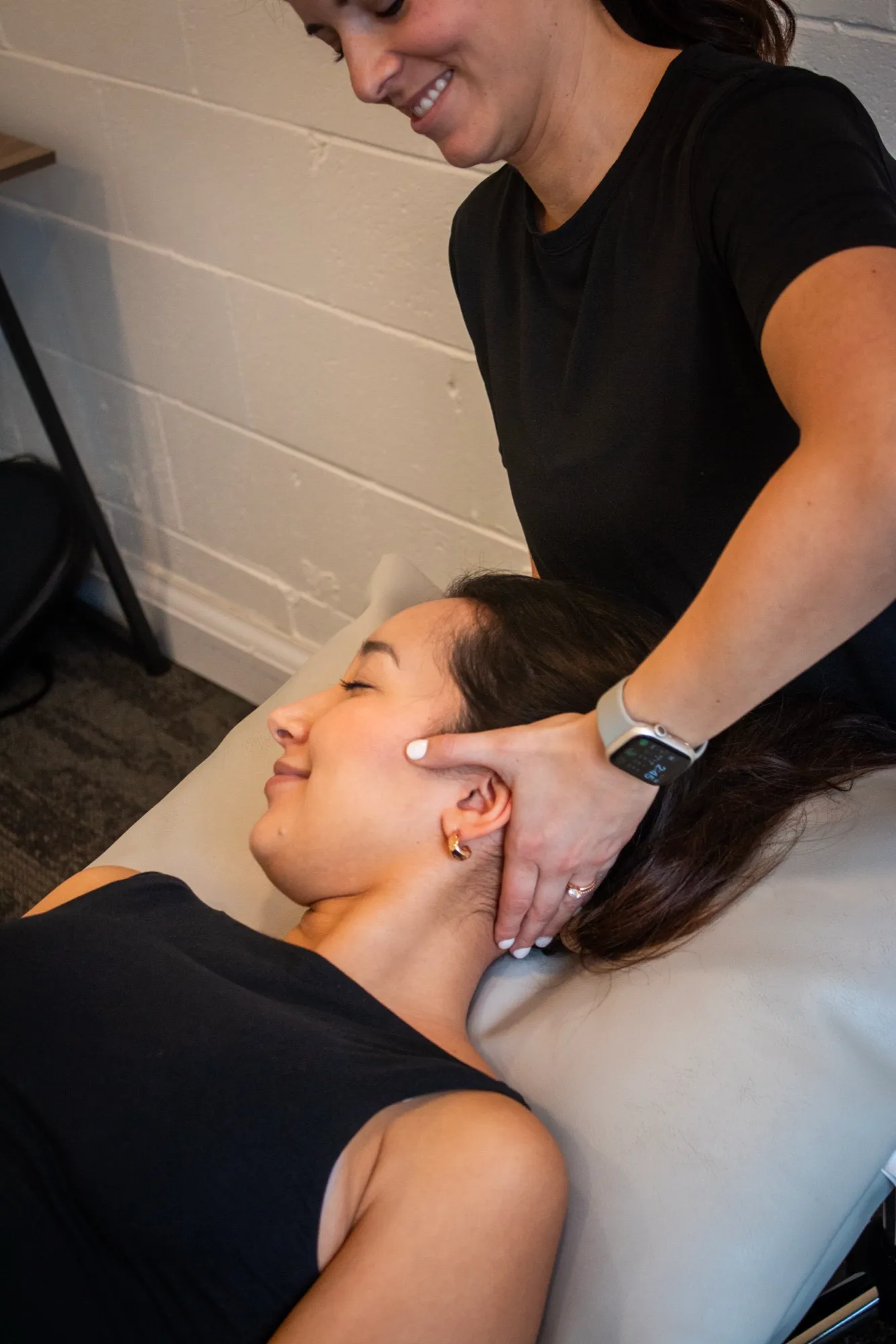 A practitioner assessing the neck and head of a patient lying on a treatment table.