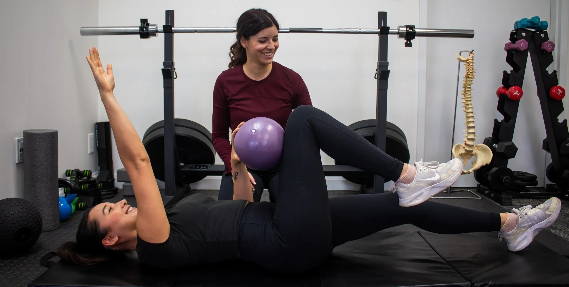 Dr. Natalie Lopez guiding a patient through a supported core exercise in the clinic gym.