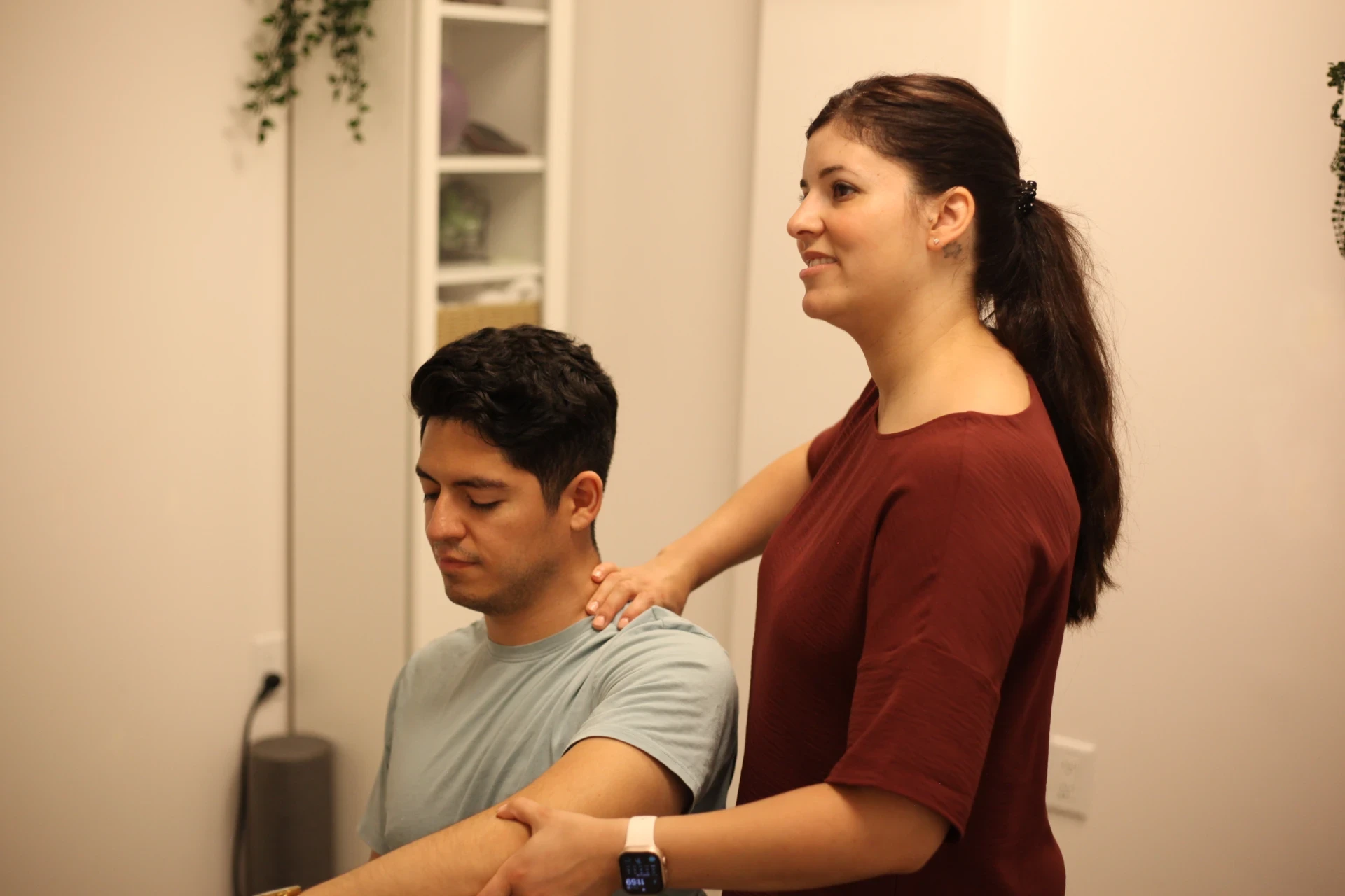 Dr. Natalie guiding a seated patient through a neck and shoulder movement assessment.
