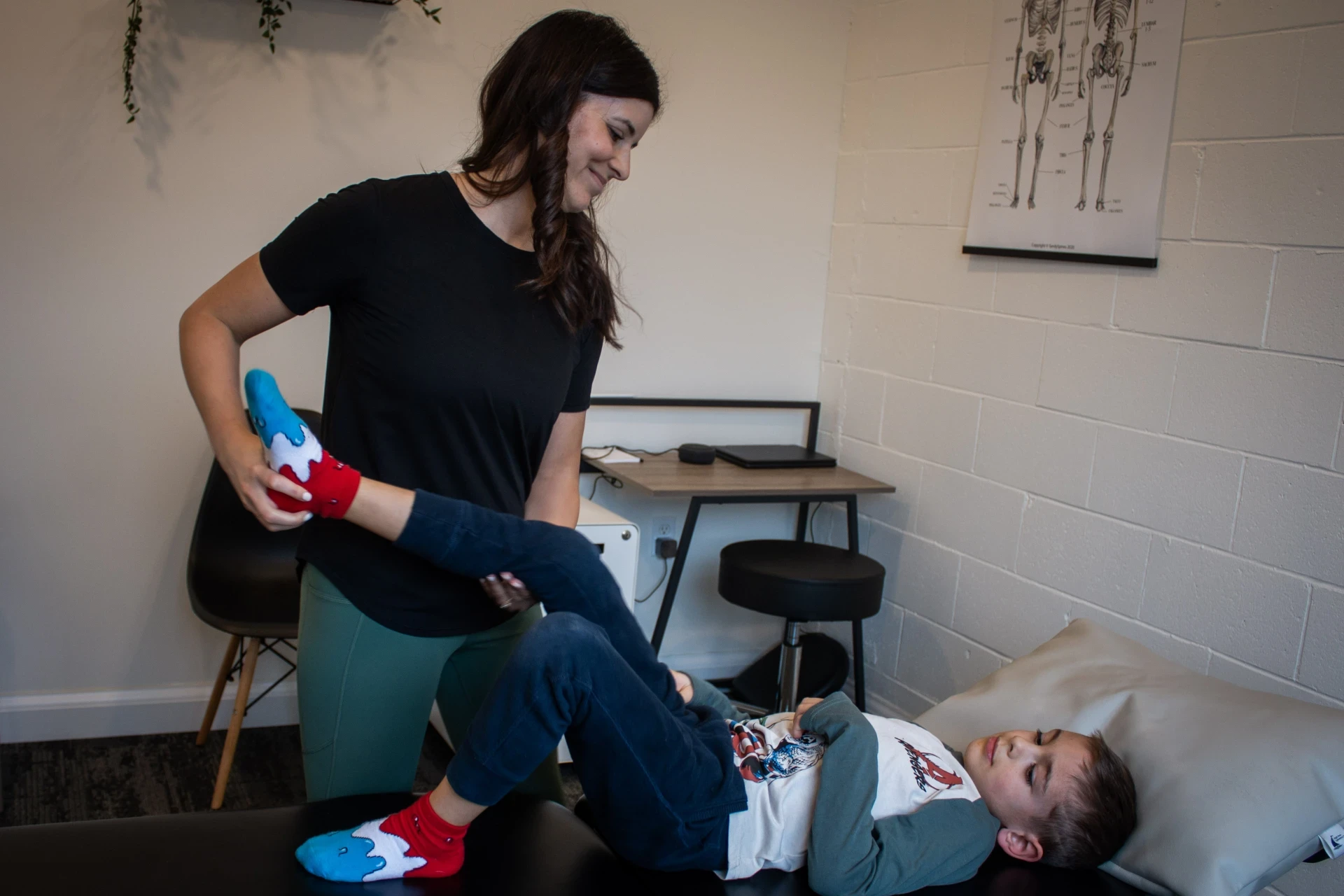 Dr. Natalie guiding a child through supported leg movement during a pediatric appointment.