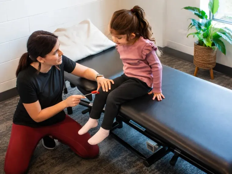 A child taking part in a gentle movement assessment with a practitioner.