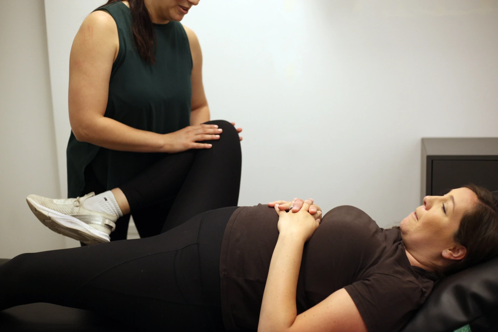 Dr. Natalie guiding a patient through supported leg and pelvic movement care.