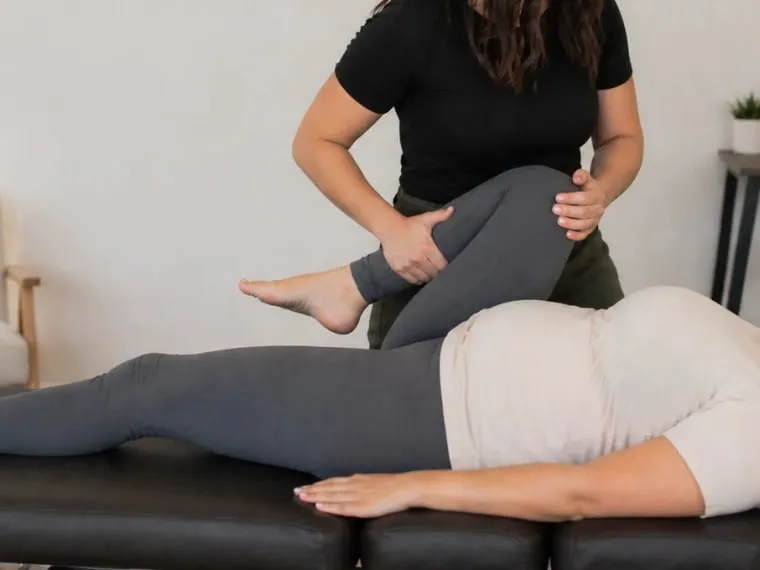A practitioner guiding a postpartum patient through a supported rehabilitation exercise.